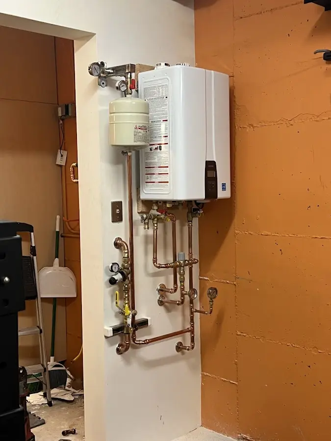 Plumbing technician inspecting water heater connections in Wauseon